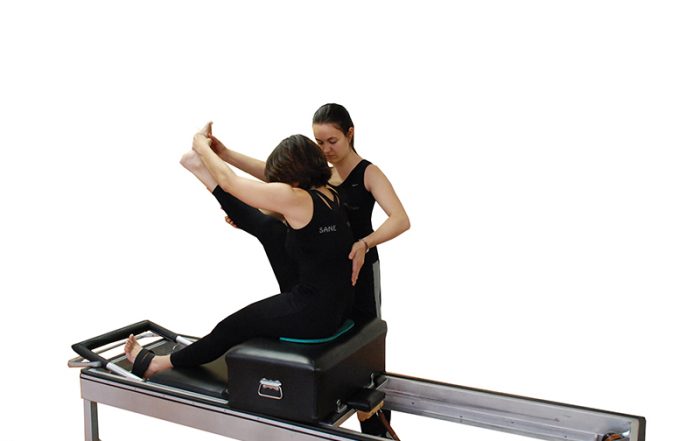 instructora-de-sane-fisio-y-pilates-en-madrid-guiando-a-alumna-en-maquina-reformer--favoreciendo-la-conciencia-del-movimiento-y-la-correccion-postural